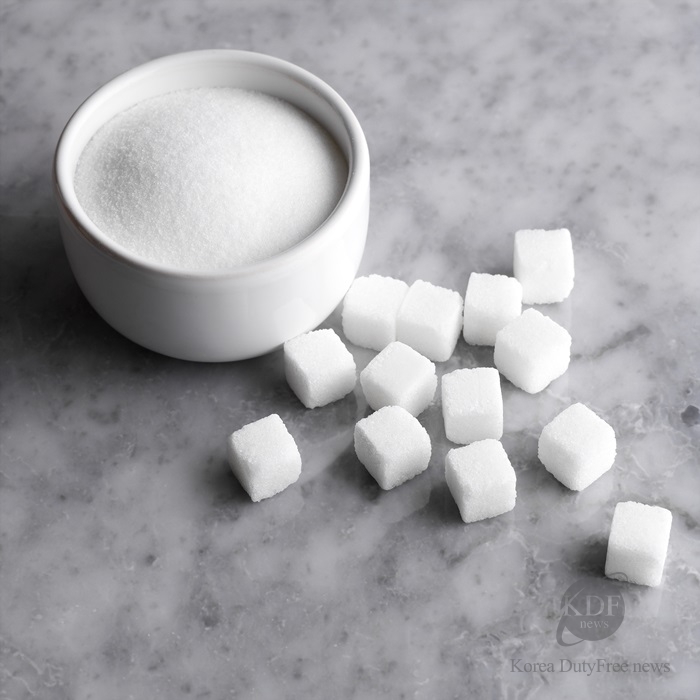 Granulated sugar in bowl with cubes on countertop